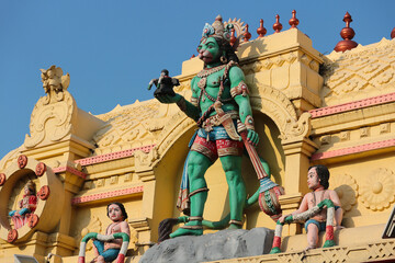 A large green Hanuman with a Shiva Lingam in his hands on the dome of a Hindu temple in India.