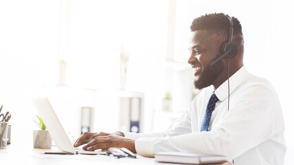 Young african american customer service agent working in office, side view, panorama with free space