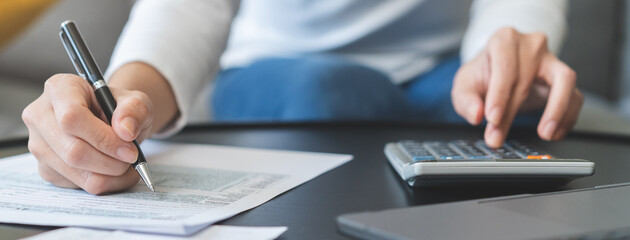 Deduction planning concept. Asian young woman hand using calculator to calculating balance prepare tax reduction income, cost budget expenses for pay money form personal Individual Income Tax Return.