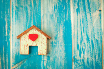 Top view of wooden house and pink heart put on the old blue vintage wood in the office, The buying a new real estate as a gift to family or the one loved concept.