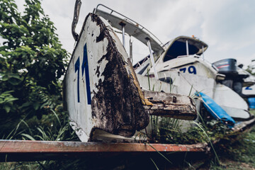 Old and rusty motor boats on a landfill surrounded by tropical forest