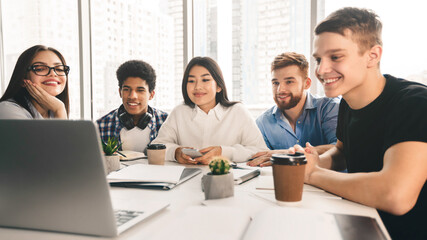 Tutorial video. Students using laptop in university library, looking at screen together, panorama