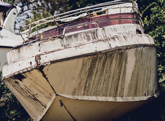 Old and rusty motor boats on a landfill surrounded by tropical forest