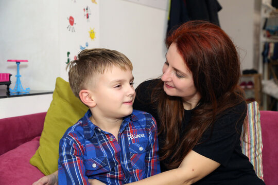 8-year-old boy in a blue shirt, sitting with his mother on the sofa, smiling, hugging, kissing, decor, birthday, holiday