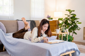 Young woman reading a book from the couch.