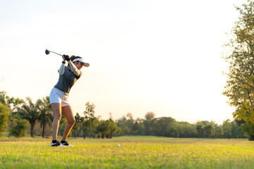 Golfer women sport course golf ball fairway. People lifestyle woman playing game golf swing tee of on the green grass sunset background. Asian female player game shot in summer. copy space for text
