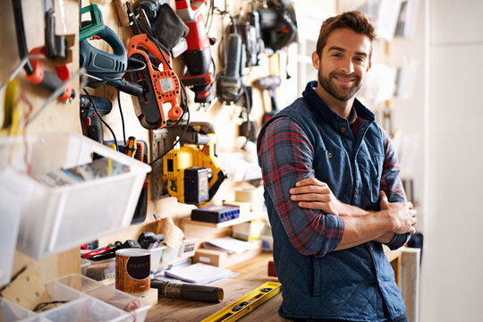 Man, arms crossed with tools and portrait in workshop, drill for diy repair and maintenance for job or skill. Artisan, handyman or carpenter with smile and confident with equipment for repairs