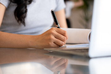 Young woman engages in note-taking at workspace.