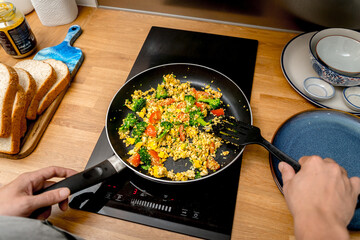 Chef at the kitchen preparing tofu scramble with vegetables