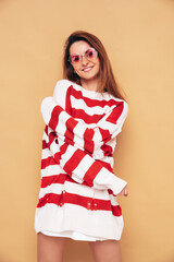 Young beautiful smiling female in trendy striped white and red sweater with holes. Carefree woman...
