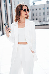 Young beautiful brunette woman in  white suit jacket.  Smiling model posing in the street ....