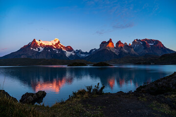 Cerro Paine Grande, Cerro Paine Grande, and Mont Almirante Nieto during a orange-red sunrise reflected in Lago Pehoe