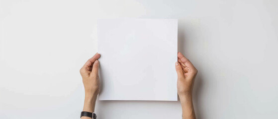 Hands presenting a blank square white paper against a minimalistic background, inviting creativity.