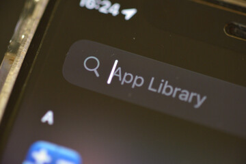 close-up view of a search box on a smartphone screen. The smartphone is held in a hand with a...