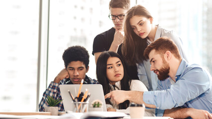Serious college students in cooperation with their project at library using laptop