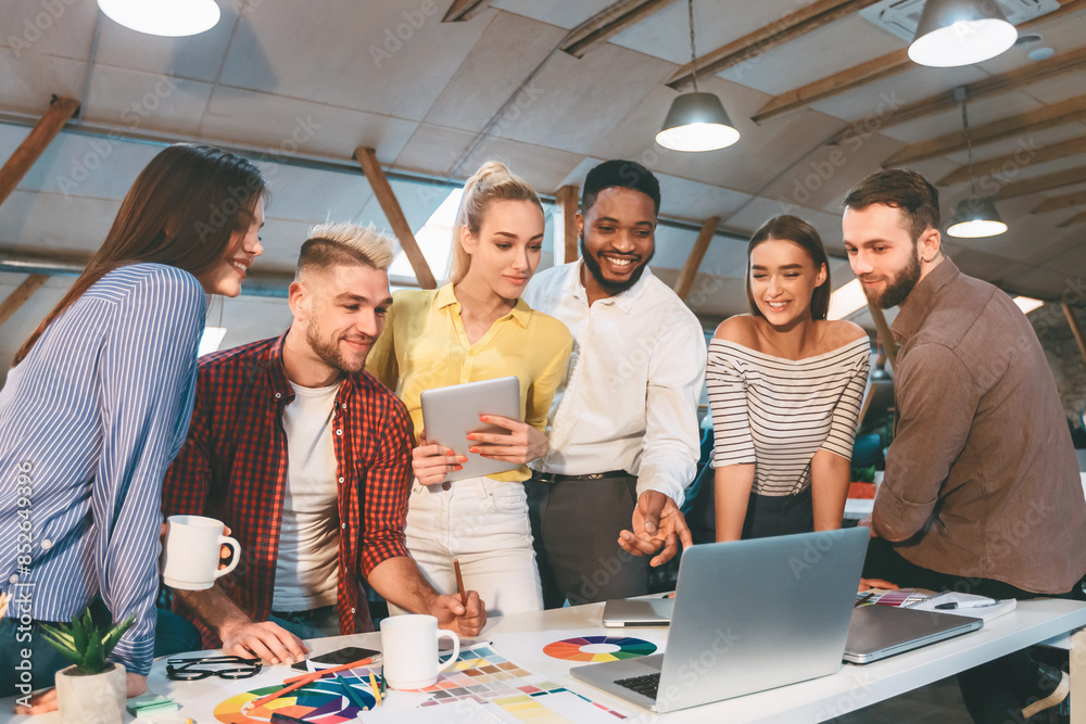 Poster people working and discussing around a table with a laptop in a business meeting or educational sett