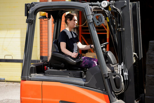 Woman operating forklift truck in industrial setting, showcasing skills and safety in material handling