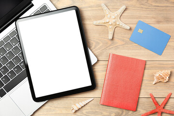 laptop, digital tablet, passport, credit card and seashells on the table, top view. vacation planning