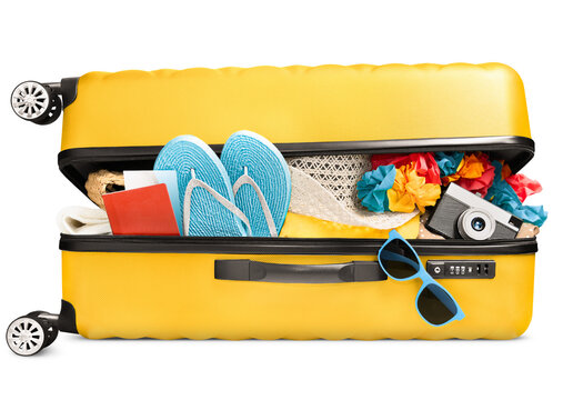 a full ajar suitcase with summer accessories, a passport and a camera lies on its side, on a white isolated background