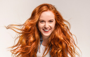 Obraz premium A woman with vibrant red hair is joyfully smiling. Her long locks cascade down her shoulders as she expresses happiness and contentment
