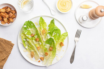 Top view of a freshly prepared Caesar salad on a white plate