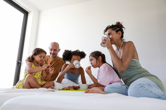 Multiethnic family enjoying breakfast in bed together