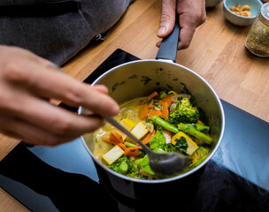 Chef at the kitchen preparing green curry with herbs and rice