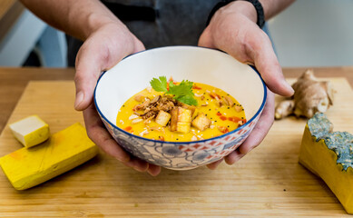 Chef at the kitchen preparing pumpkin porridge with tofu and vegetables