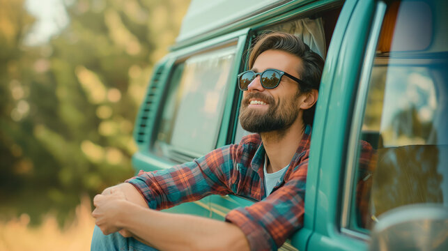 Happy man leaning on a vintage camper van enjoying nature