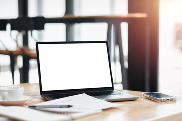 A laptop is open on a table with a cup of coffee and a cell phone. The laptop screen is blank, and...
