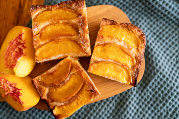 A dessert made of sliced peaches is on a wooden cutting board. The dessert is covered in sugar and looks delicious.