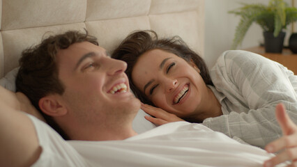 Caucasian couple man woman lying on bed home discussing plans chatting talking laughing happiness girlfriend boyfriend honeymoon romance togetherness intimate loving affection relax unity family smile