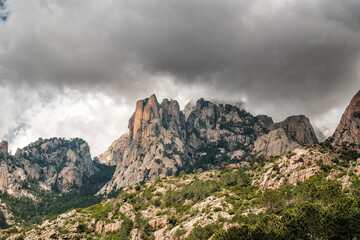 Dark clouds over the Aiguilles de Bavella, needle like rocky mountain peaks surrounded by pine forest and maquis in the centre of Corsica