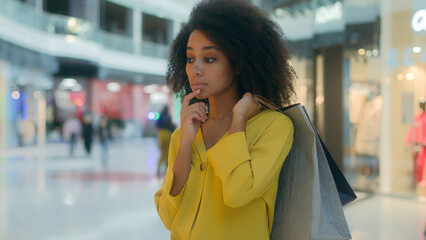 African American woman going walk shopping mall buyer client holding packages think choose pensive...