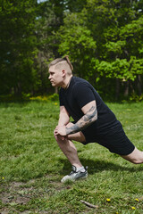 Caucasian male athlete doing warm-up before training outdoors in summer park