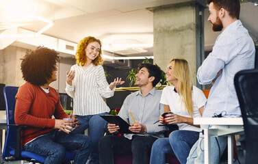 Several individuals are seated at a table engaged in conversation. They appear to be actively listening and participating in the discussion, gesturing and making eye contact