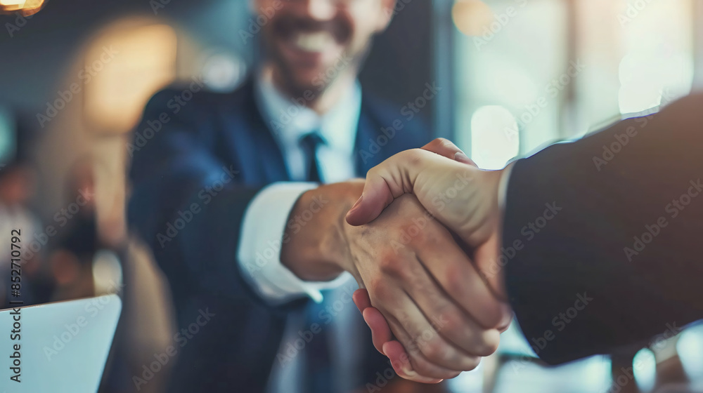 Poster close-up of a firm handshake between professionals with a smiling businessman in the background