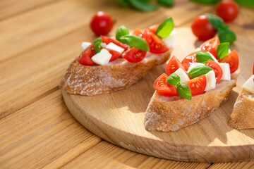 Sandwich with tomatoes, mozzarella cheese and basil on wooden board. Traditional Italian appetizer, toast, snack or antipasto. Vegetarian food. Healthy eating. Mediterranean food.