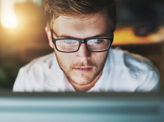Man, computer and glasses at night in office, research and web designer for proposal. Male person, employee and reading or website for online tasks, project management and reflection on late shift