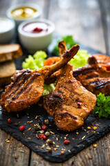 Lamb chops with bone, fresh vegetables and sauces on wooden table
