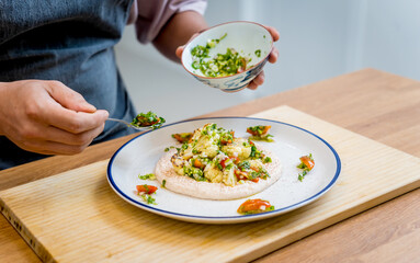 Chef at the kitchen preparing bean porridge with cauliflower and vegetables