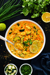 Curry soup with chicken meat, zucchini and vermicelli  noodles on black background
