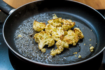 Chef at the kitchen preparing bean porridge with cauliflower and vegetables