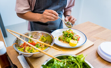 Chef at the kitchen preparing spicy glass noodle salad