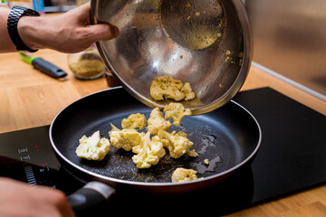 Chef at the kitchen preparing bean porridge with cauliflower and vegetables