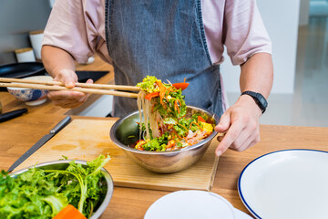 Chef at the kitchen preparing spicy glass noodle salad