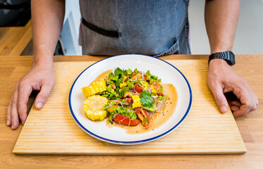 Chef at the kitchen preparing spicy glass noodle salad