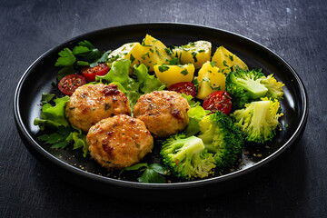 Cooked meatballs, boiled broccoli, boiled potatoes and fresh vegetables on wooden table

