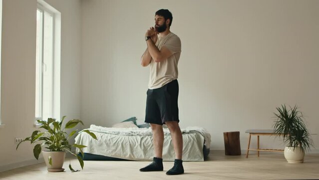 Millennial man training at home, exercising hands at bedroom