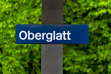 Close-up of blue and white metal sign at railway station of Swiss village of Oberglatt on a cloudy spring day. Photo taken June 15th, 2024, Oberglatt, Canton Zurich, Switzerland.